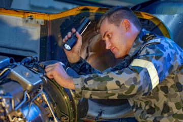 Person in uniform inspecting engine