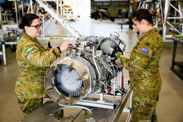 Two people inspecting a helicopter engine